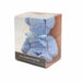 A bear-shaped towel gift in a clear plastic cube package, featuring a light blue plush towel bear with a matching blue ribbon bow and a dark label at the bottom.