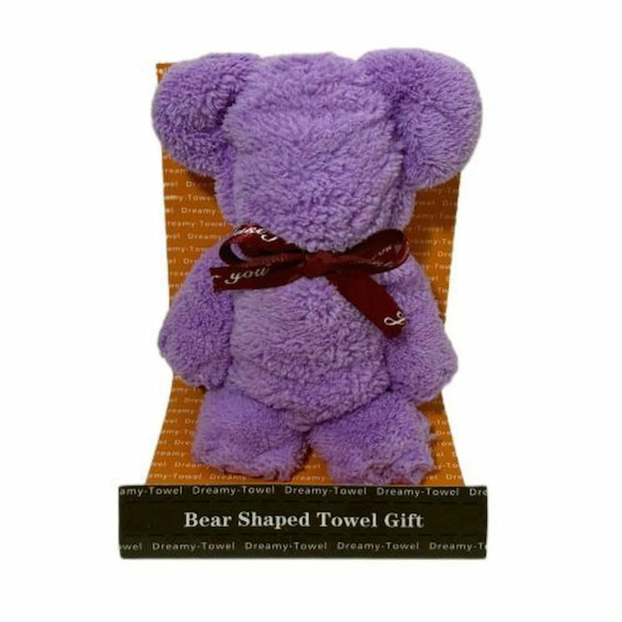 A purple plush teddy bear-shaped towel gift sitting in an orange patterned chair, tied with a dark red bow that says 'you are', with a black label at the bottom reading 'Bear Shaped Towel Gift'.