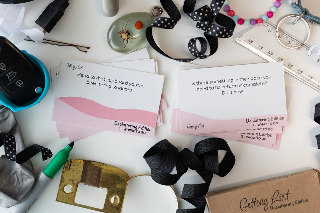 Desk with decluttering cards, ribbons, and other items on a white surface