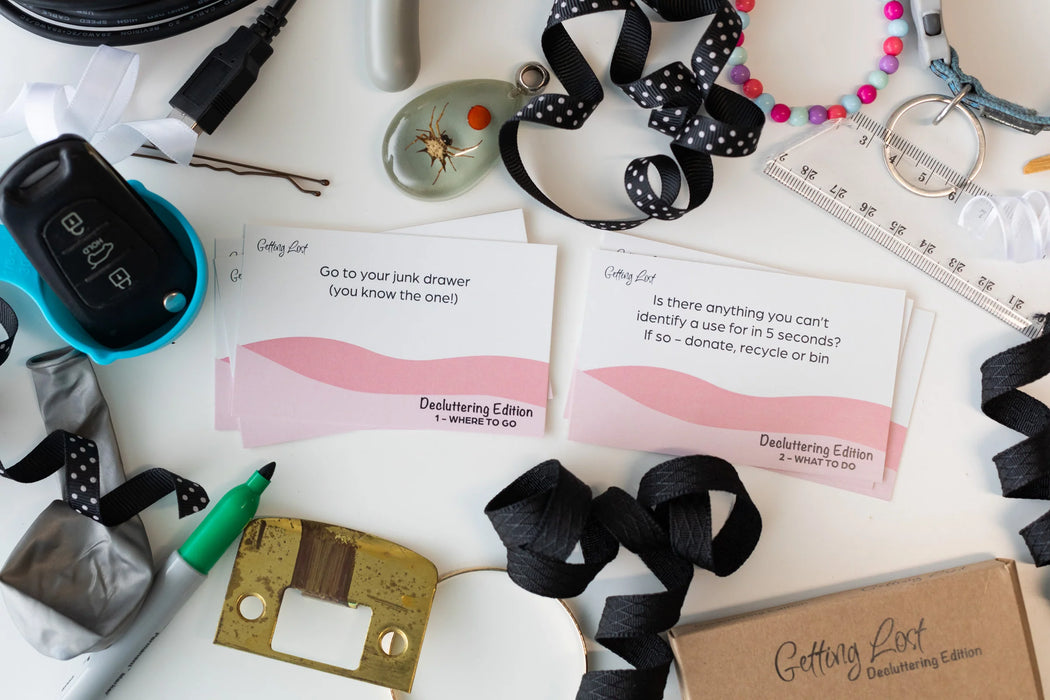 Desk with office supplies, ribbons, and decluttering cards on a white surface