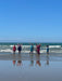 Group of people on a beach with arms raised, enjoying the view.