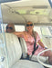 Two women sitting inside a vintage vehicle with a white interior.