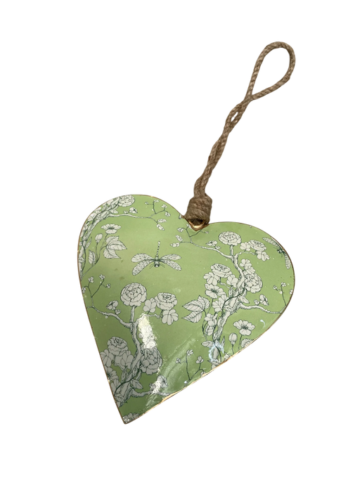 A heart-shaped decorative hanging ornament with a light green background, white floral and dragonfly pattern, and a natural jute hanging loop.