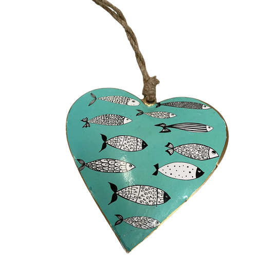 A heart-shaped metal hanging ornament with a turquoise background, decorated with black and white patterned fish, and suspended by a natural twine string.
