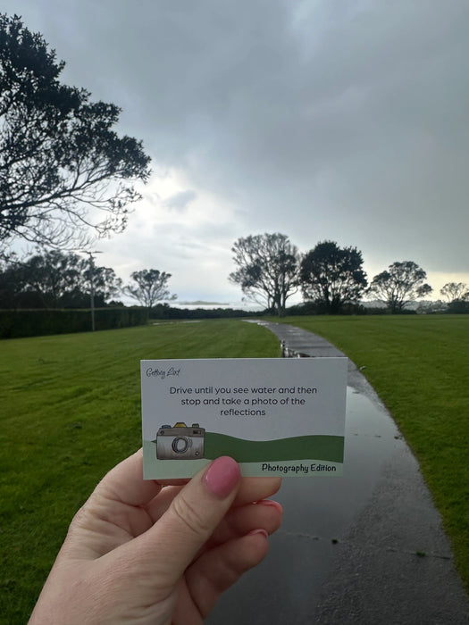 Hand holding a card with instructions on a road with grass and trees in the background