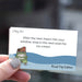 Hand holding a card with a humorous road trip message and illustration of a car with luggage.