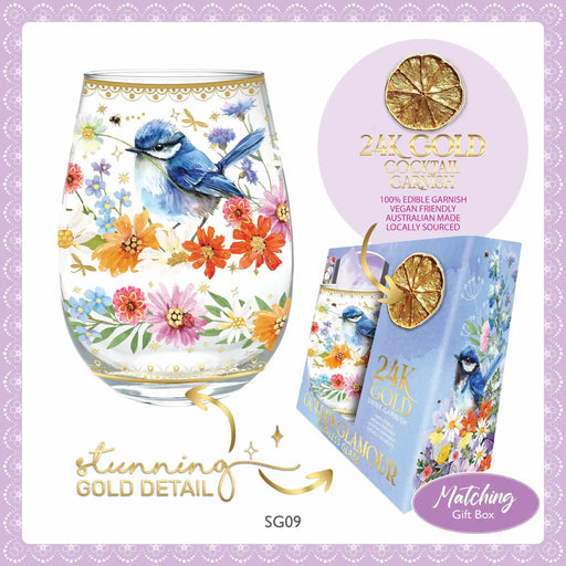 Decorative glass with floral and bird design, 24K gold cocktail carafe, and matching gift box on a light purple background.