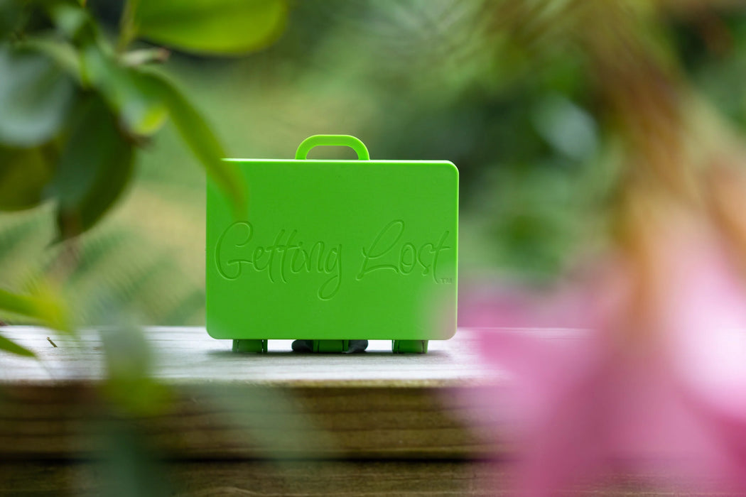 Green suitcase-shaped object with 'Getting Lost' text on a blurred natural background