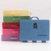 Stack of colorful plastic suitcases with a blue one labeled 'Getting Lost Road Trip Edition' on a light gray background.