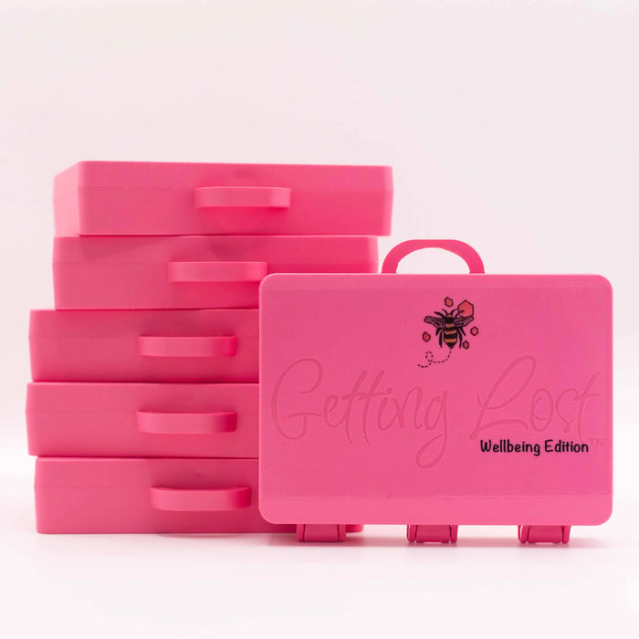 A set of bright pink plastic drawer organizers with handles, shown with five stacked drawers and one open-front organizer in front. The front organizer has a bee illustration and the text 'Getting Lost' and 'Wellbeing Edition'.
