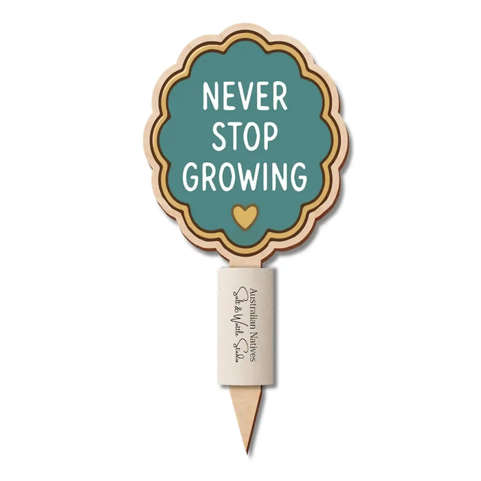A wooden garden stake with a scalloped sign that reads 'NEVER STOP GROWING' in white text on a teal background, with a small gold heart and layered wood borders, on a white background.