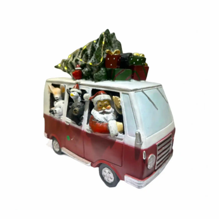 A festive Christmas-themed miniature van decoration with Santa Claus driving, animals in the back seats, a Christmas tree, and wrapped gifts on top, isolated on a white background.
