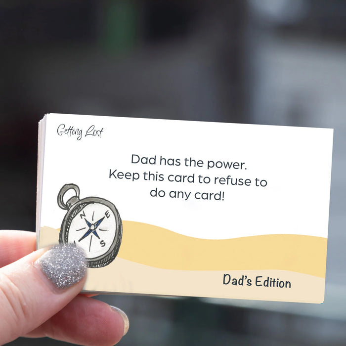 Card held by a hand with text and compass illustration, labeled 'Dad's Edition'.