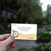 Hand holding a card with a humorous message about socks for Father's Day, with a blurred outdoor background.