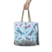 A tote bag with a dragonfly and floral print, held by a hand against a plain white background.