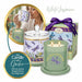 A white jasmine scented candle set by Leioh, featuring a sage green double-wick candle with a dragonfly design, a matching glass jar with lid, a purple ribboned gift box, and a circular inset showing a woman drinking from a matching mug.