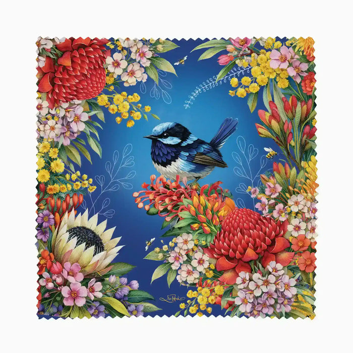 A square fabric napkin or coaster with a scalloped edge, featuring a vibrant tropical floral border and a blue-and-white bird on a rich blue background.