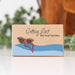 Cardboard box with 'Getting Lost Girls Road Trip Edition' text and sunglasses illustration on a blurred background