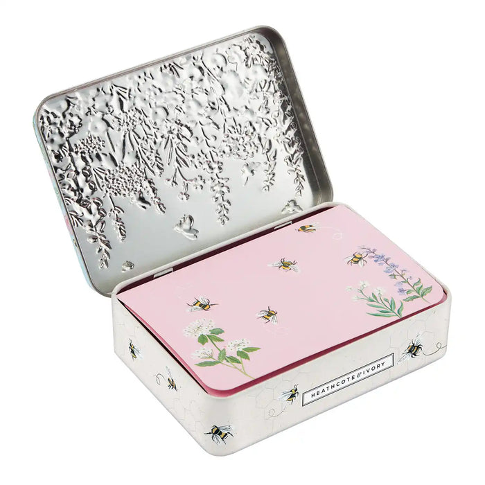An open silver metal tin with a pink lid decorated with illustrations of bees, flowers, and leaves. The brand name 'HEALTHCUTE DIVORY' is visible on a small label on the front of the tin.