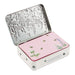 An open silver metal tin with a pink lid decorated with illustrations of bees, flowers, and leaves. The brand name 'HEALTHCUTE DIVORY' is visible on a small label on the front of the tin.