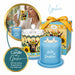 A decorative candle set shown on a white background with product packaging, a glass jar candle, a blue candle vessel, and a gift box tied with a yellow ribbon. The candle features a cow and sunflower illustration, and the packaging and labels include the text 'Lycchee' and 'Hello Sunshine'.