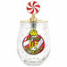 A clear stemless wine glass with a gold rim and a decorative top featuring a red and white swirl candy lollipop on a gold post. The front of the glass is printed with a colorful graphic that reads 'BOTTOMS UP GRINCHES' with a yellow penguin and red, black, and white circular design, accented with small multicolored confetti dots.