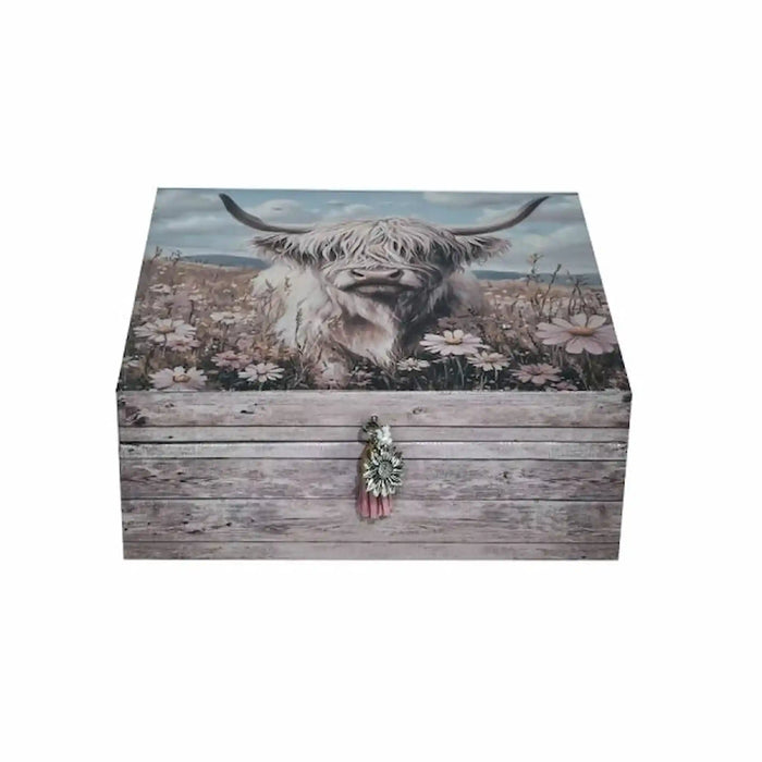 A rectangular wooden storage box with a rustic weathered gray finish, featuring a printed design of a Highland cow in a field of white flowers on the lid, with a small decorative clasp on the front.