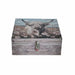 A rectangular wooden storage box with a rustic weathered gray finish, featuring a printed design of a Highland cow in a field of white flowers on the lid, with a small decorative clasp on the front.