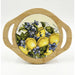 A round bamboo serving board with two side handles and a central printed illustration of lemons, green leaves, and blue flowers on a white background.
