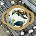 Decorative plate with turtle design on a wooden surface with shells around