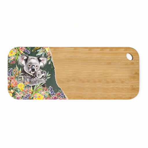 A rectangular bamboo cutting board with rounded corners and a small oval hole in the top-right corner. The left side features a decorative printed border with a watercolor-style koala holding a baby koala, surrounded by colorful flowers and green leaves on a dark background.