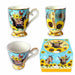 Three views of a decorative ceramic mug with a matching gift box, featuring a cow, sunflowers, and birds on a light blue background with gold trim.