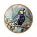 Midnight Australiana ceramic trivet featuring a black cockatoo with a yellow cheek patch among native foliage. 