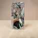 A packaged mini bloom car diffuser with a clear plastic bag, showing the wooden flower-shaped diffuser, sponge, and scent card on a light beige surface against a neutral beige background.