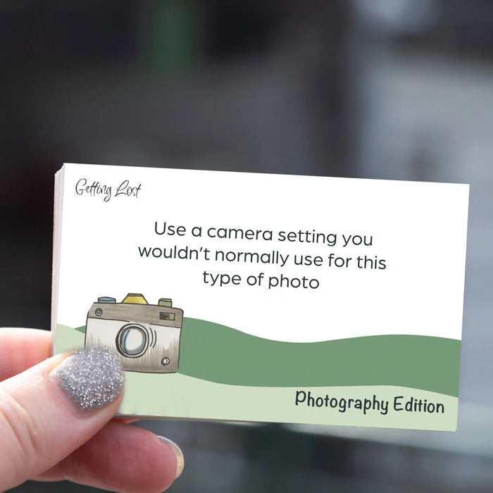 Hand holding a business card with camera illustration and text on a blurred background