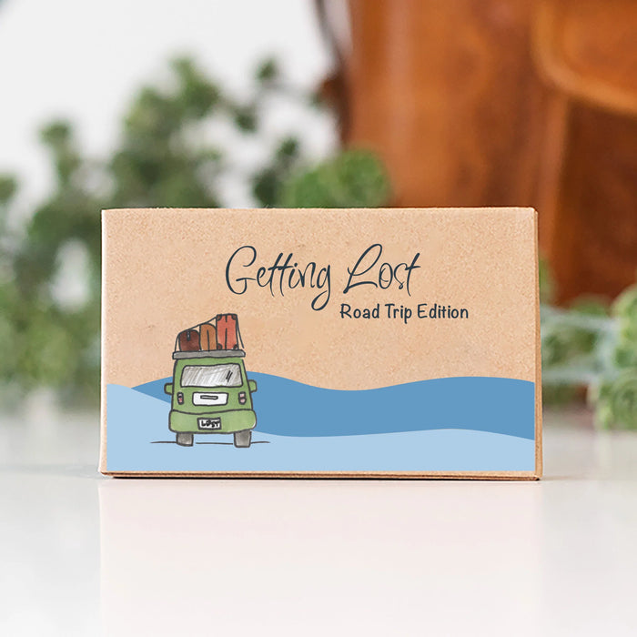 Cardboard box with a cartoon van and 'Getting Lost Road Trip Edition' text on a blurred background
