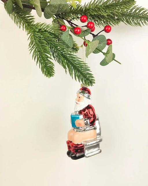 Santa on toilet Christmas ornament with glossy red suit, boots and white beard, approximately 11cm tall