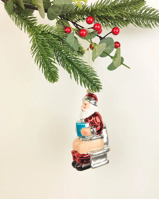 Santa on toilet Christmas ornament with glossy red suit, boots and white beard, approximately 11cm tall