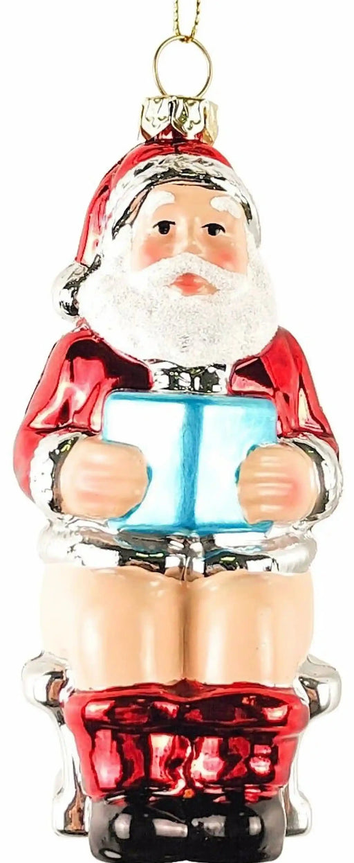Santa on toilet novelty glass Christmas ornament reading a blue book, front view on a white background