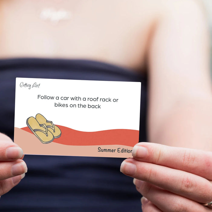 Hand holding a card with text and a flip-flop illustration, with a blurred background.