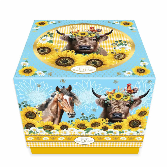 A decorative square gift box featuring a highland cow with a sunflower crown, a horse, and roosters, set against a sky blue and yellow gingham background with bold sunflower and daisy illustrations. Photographed on a white background