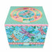 A square decorative gift box in mint green with gold polka dots, featuring colourful dragonfly illustrations in purple, pink, and orange over a background of blue and teal hydrangea florals. Photographed on a white background.