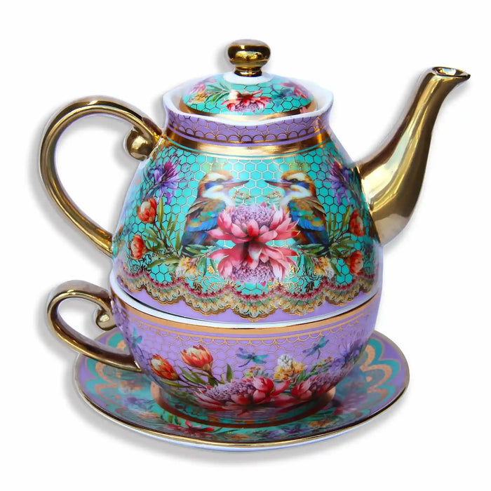 An ornate ceramic teapot with a matching saucer and cup, decorated with intricate floral and bird motifs on a light purple background with gold trim.