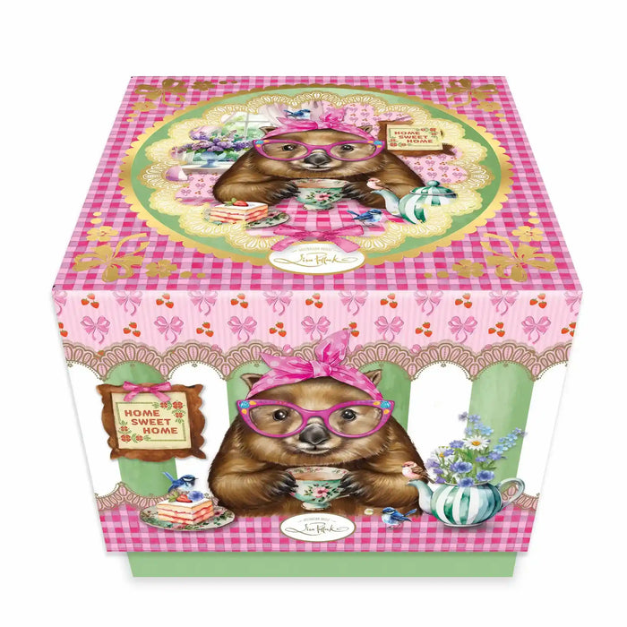 A decorative gift box featuring the Wonda Wombat character wearing pink glasses and a headband, surrounded by pink gingham patterns, floral illustrations, and tea-time motifs, photographed on a clean white background.