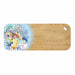 A rectangular wooden cutting board with rounded corners and a small oval hole in the top right. The left side features a decorative printed illustration with a bouquet of flowers, a yellow teapot, a teacup, bluebirds, and a lace border over a light blue background.