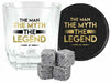 A clear rocks glass with the phrase 'THE MAN THE MYTH THE LEGEND' printed in black and gold, shown alongside a round black coaster with matching text, plus four gray ice cubes on a white background.