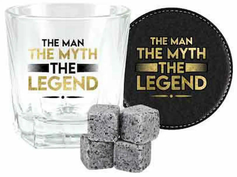 A clear rocks glass with the phrase 'THE MAN THE MYTH THE LEGEND' printed in black and gold, shown alongside a round black coaster with matching text, plus four gray ice cubes on a white background.