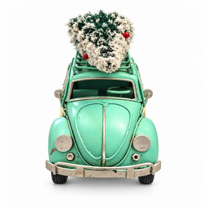 A vintage mint green toy or decorative Volkswagen Beetle car with a small frosted Christmas tree on its roof rack, photographed against a plain white background.