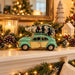 A vintage-style toy car in mint green and cream sits on a decorated Christmas mantel with pinecones, evergreen garland, warm string lights, candles, and holiday decor in the background.