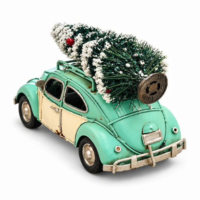 A vintage-style teal and cream toy car with a small Christmas tree strapped onto the roof rack, photographed on a clean white background.